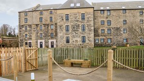 A stone building with multiple windows and a wooden fence. - Bay View (Belford)