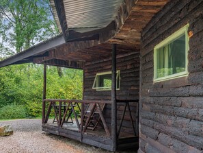 Eine rustikale Holzhütte mit Veranda, Überdachung und Fenster.