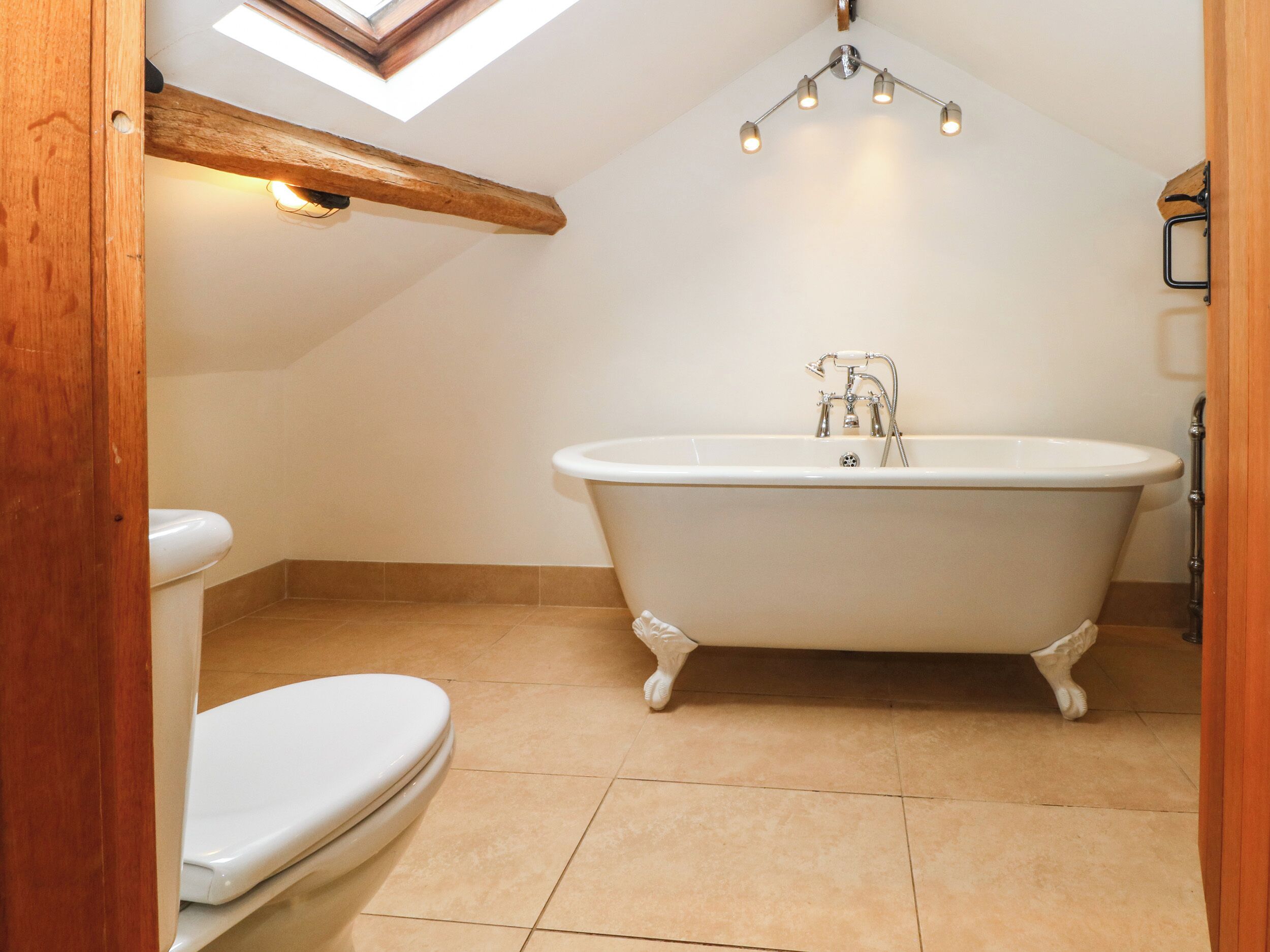 A bathroom with a freestanding bathtub, a toilet, and a skylight.
