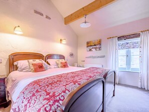 Un dormitorio con cama, mesitas de noche, una ventana con cortinas y un cuadro en la pared.