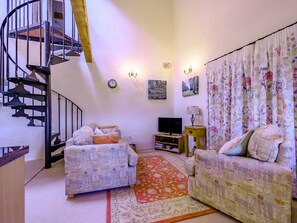Una sala de estar acogedora con un sofá, un televisor y una escalera.