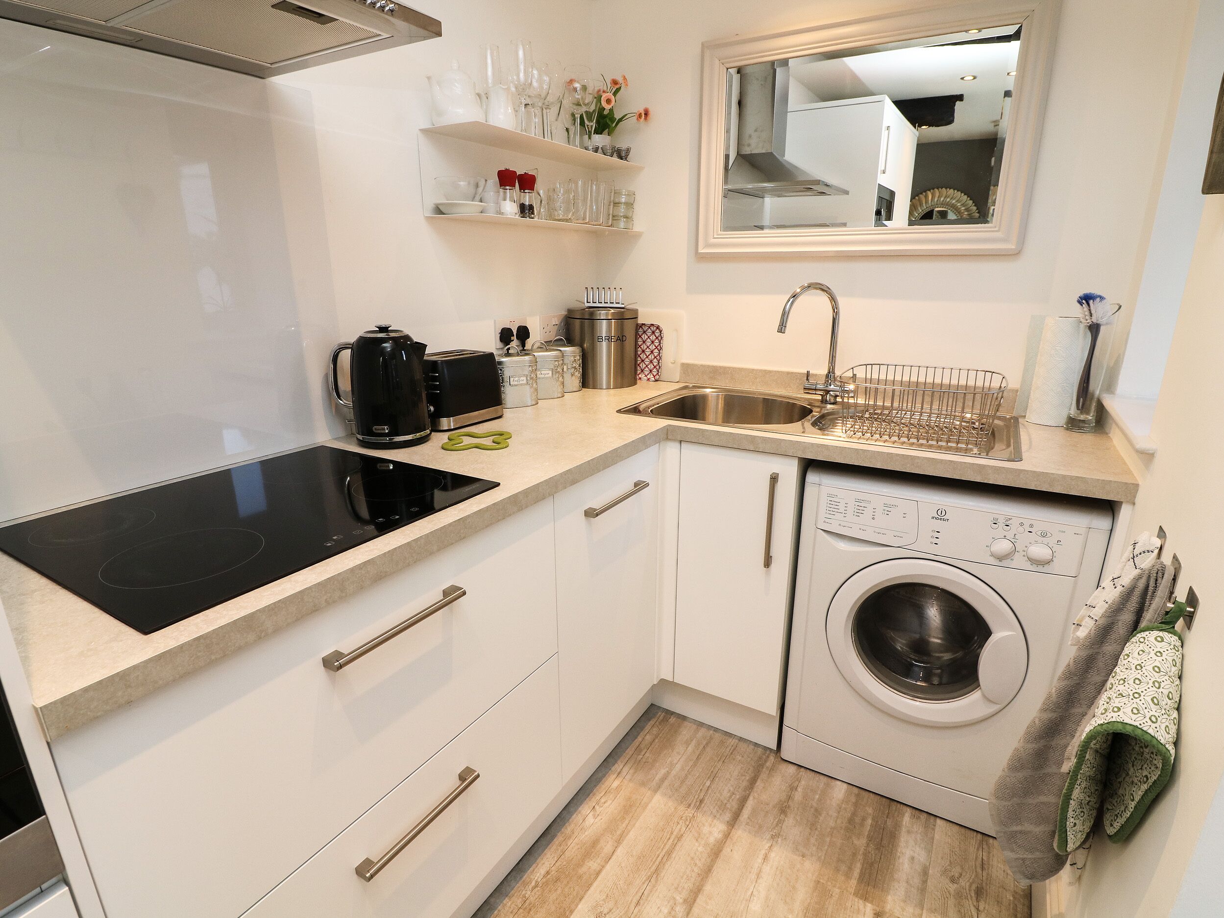 Een functionele keuken met een ingebouwde kookplaat, een spoelbak en een wasmachine.