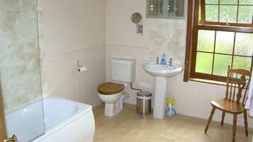 A bathroom with a bathtub, toilet, sink, and a window.