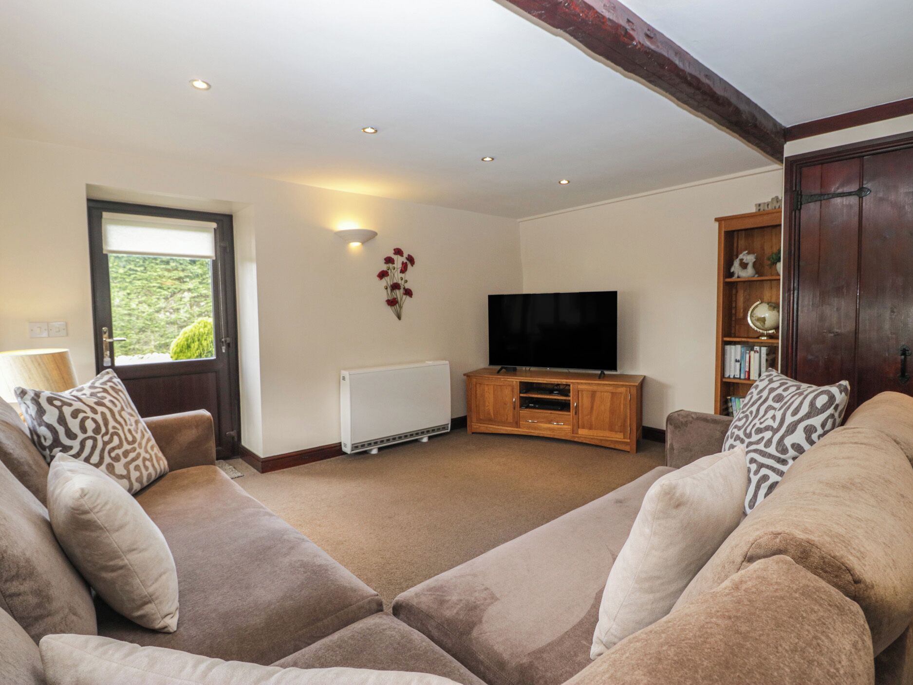 A living room with a sofa set, a television, a radiator, and a bookshelf.
