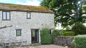 A stone building with a small garden area featuring rocks, shrubs, and a pathway. - The Cottage (Buxton)