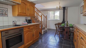 Une cuisine avec des meubles de rangement en bois, une cuisinière et un coin repas comprenant des chaises et une table.