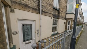 A residential building with a white facade, a metal fence with spherical finials, and a door with a decorative glass panel. - Apartment 6 (Whitby)