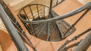Una escalera de caracol con barandales metálicos ornamentales y un rellano alfombrado.
