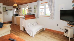 A cozy room with a bed, a TV, a small kitchen area, and a dining table. - The Log Cabin (Craven Arms)