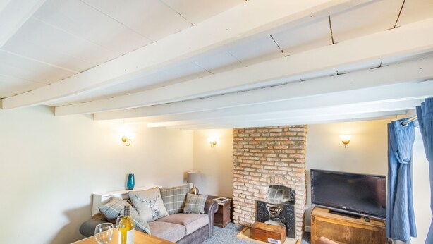 Una sala de estar acogedora con una mesa de madera, un sofá, un televisor y una chimenea de ladrillo.