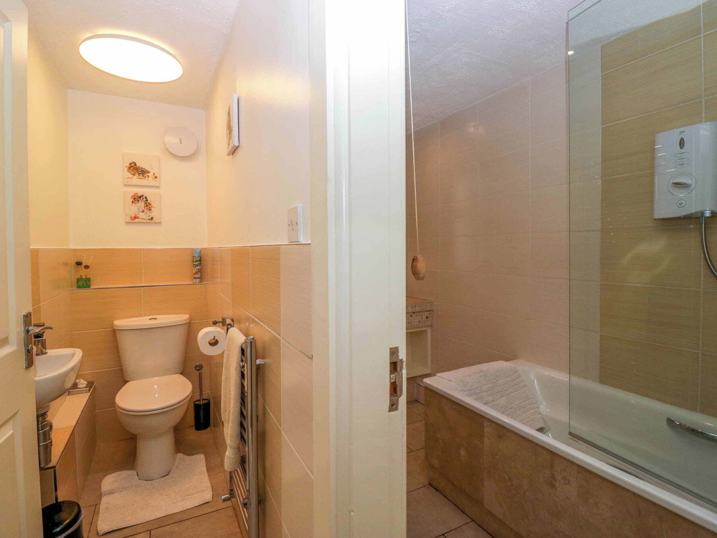 A compact bathroom with a toilet, sink, and shower.