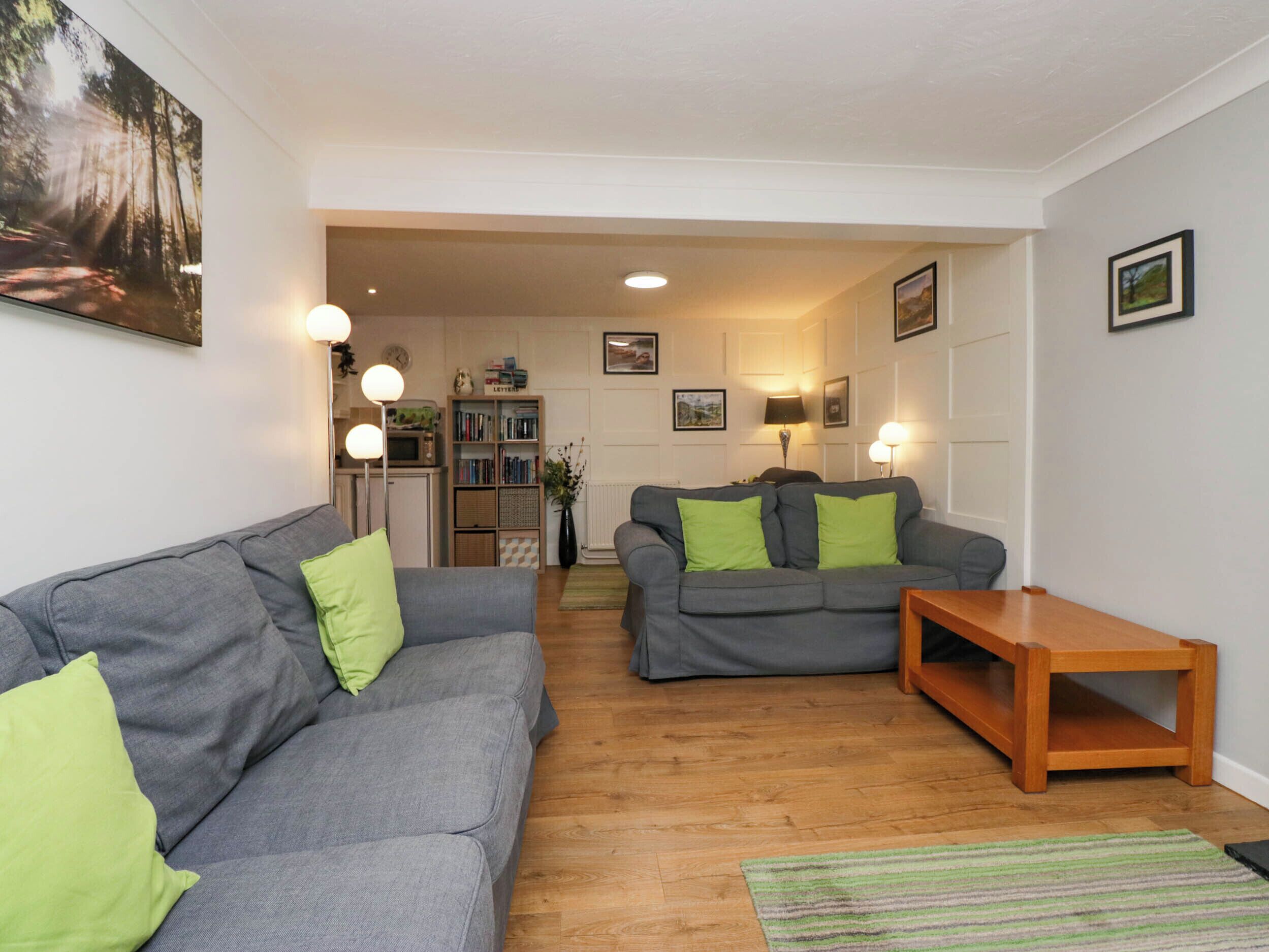 A living room with two grey sofas, a wooden coffee table, and a bookshelf.