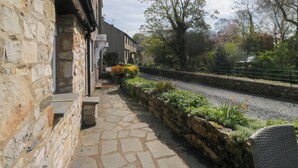 A stone-paved pathway leading to a building with a stone wall and satellite dishes. - The Old Mill (Grange-over-Sands)
