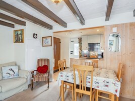 Una sala de estar acogedora con un sofá, un sillón a rayas y una mesa de comedor con mantel estampado.