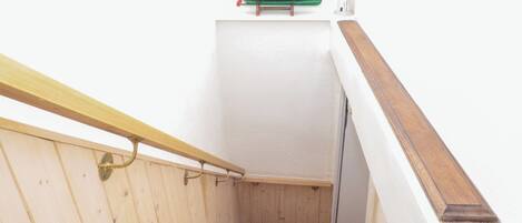 A narrow stairway with wooden handrails and a white wall.