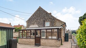 A stone house with a conservatory, a brick exterior, and a small front yard. - Violet Cottage (Thetford)