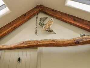 Une pièce avec un plafond en pente, des poutres en bois et une porte blanche.