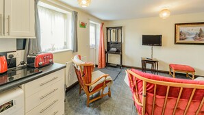 Una cocina compacta con tostadora, tetera y un pequeño comedor con una silla y mesa.