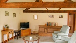 Un salon avec un plafond en bois, une télévision, une bibliothèque, un canapé et une table basse.