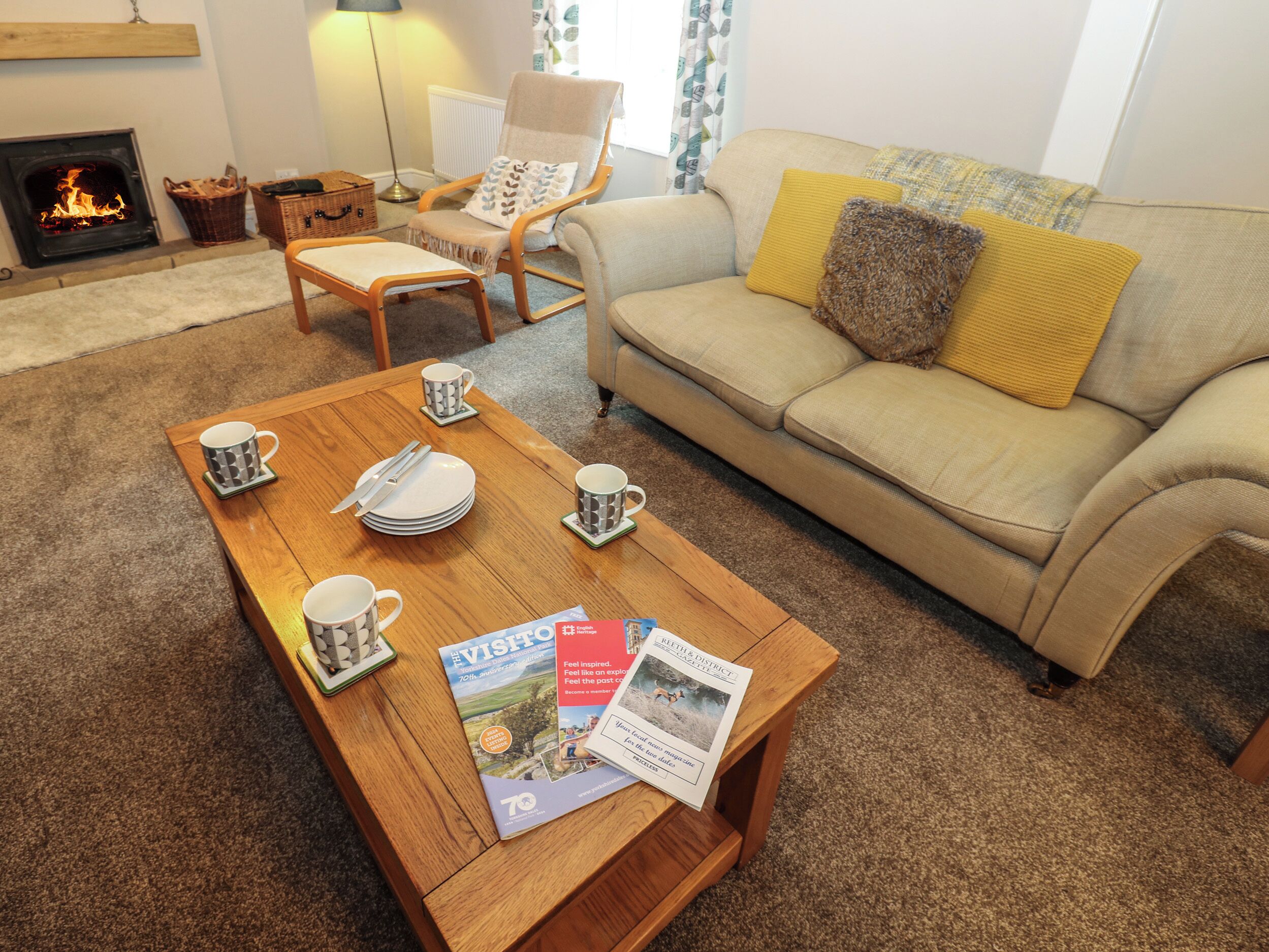 Un salon chaleureux avec une cheminée, un canapé, une table basse en bois sur laquelle sont posés des magazines et un fauteuil.