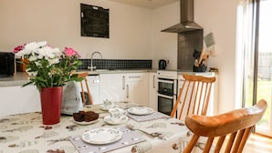 Cocina moderna con armarios blancos, extractor de acero inoxidable y un comedor con mesa para cuatro.