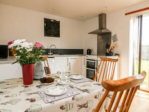 Enjoy meals in this kitchen with a stainless steel range hood, oven, and large window offering a view of the outdoors.