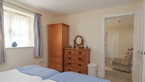 Una camera da letto con due letti, una cassettiera in legno, uno specchio e una finestra con tende.