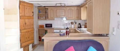 A compact kitchen with wooden cabinets, a microwave, and a coffee maker.