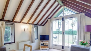 A room with a TV, a table, a sofa, and a window with curtains.