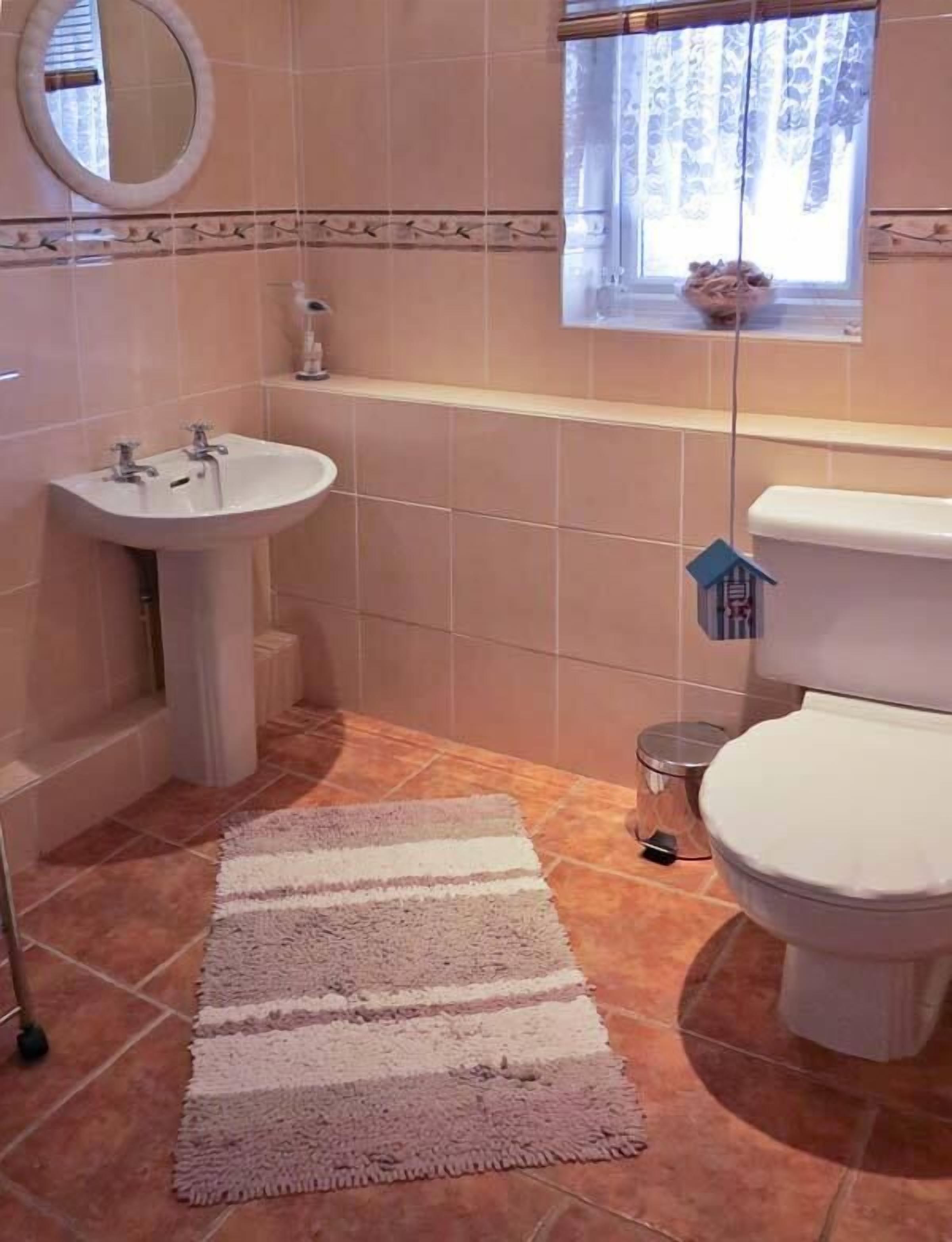 A bathroom with a sink, toilet, and a window with curtains.