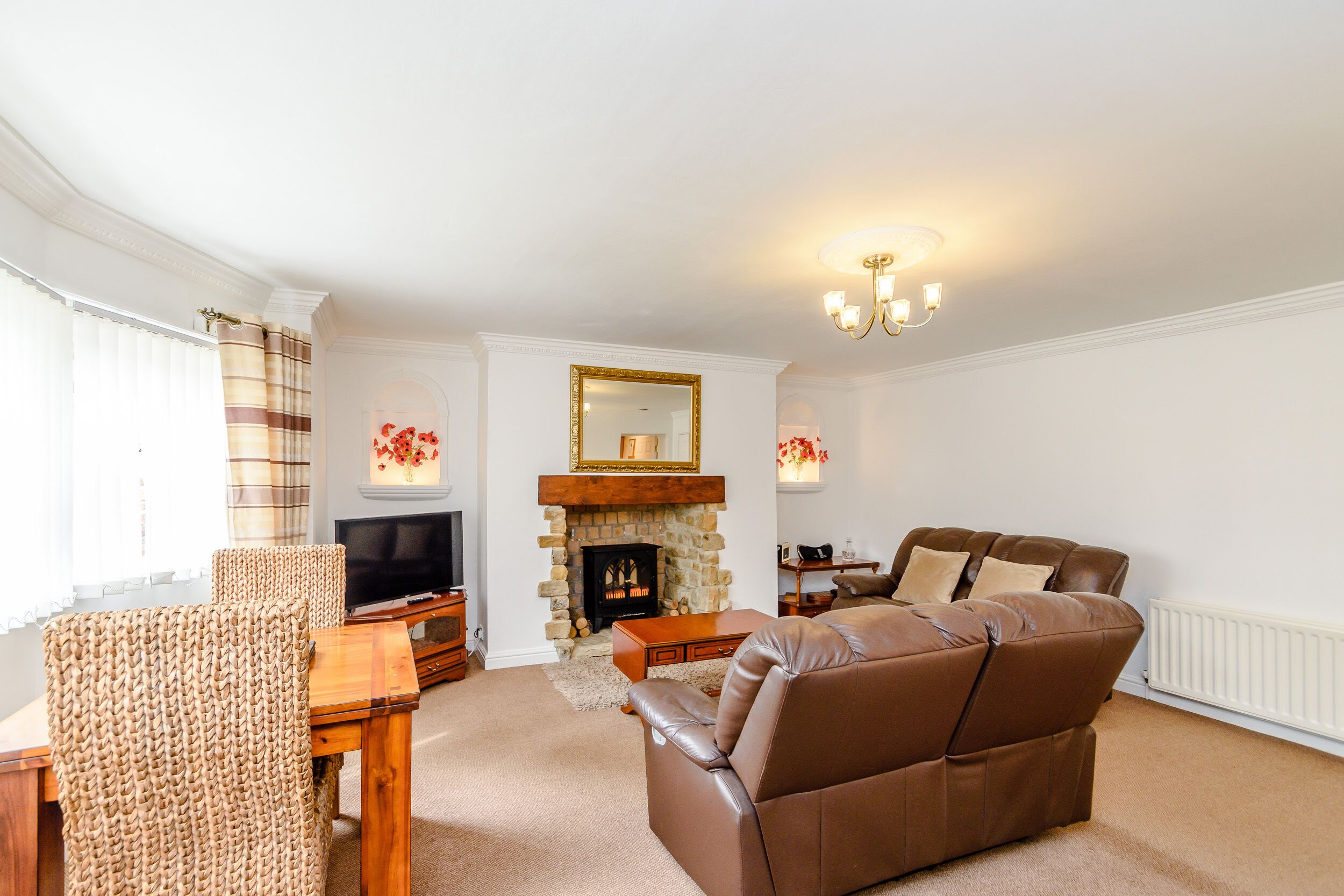 A living room with a fireplace, leather sofa, and a television.