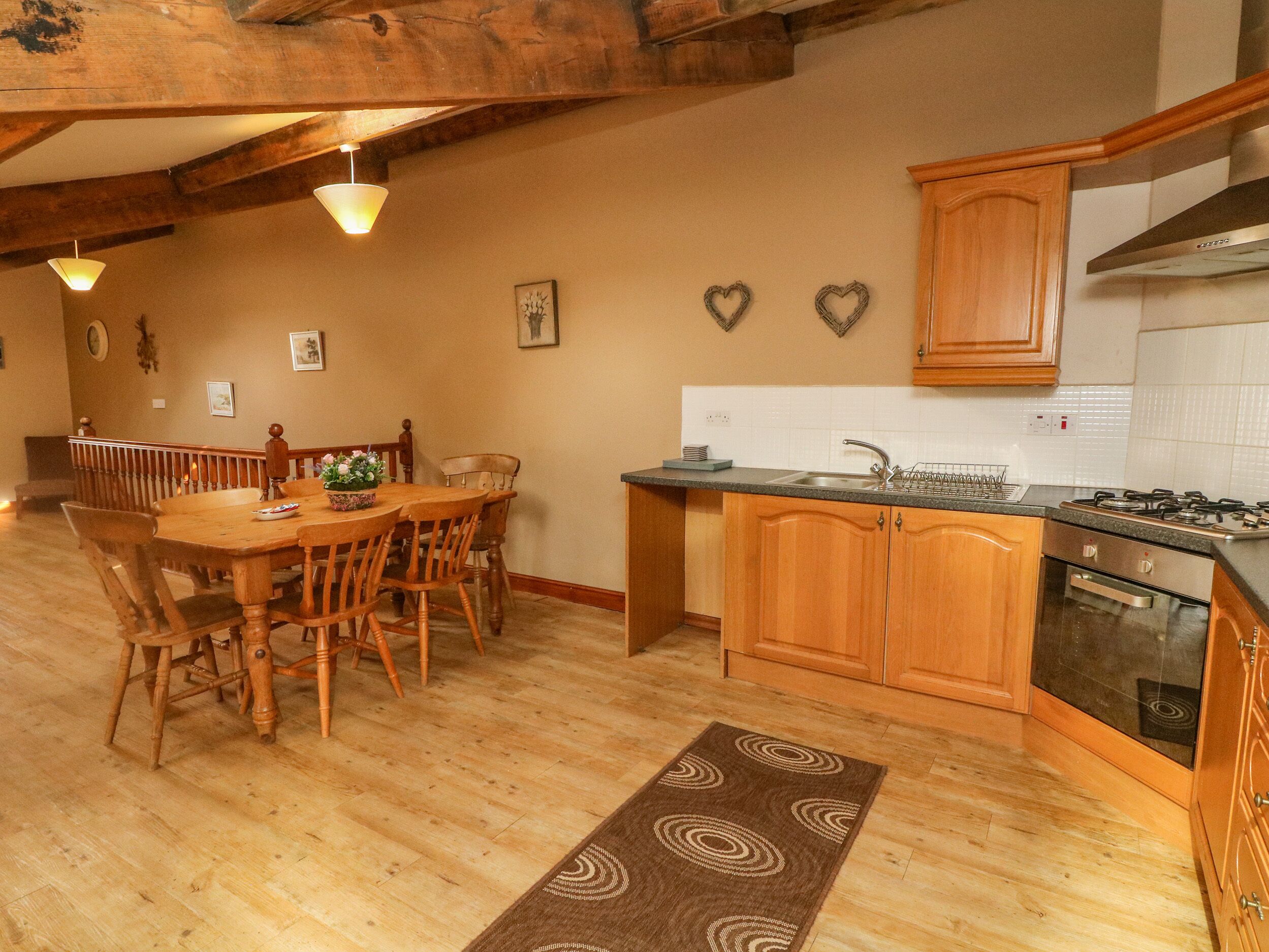 A wooden dining table with chairs, a kitchen with wooden cabinets, a stove, and a sink.