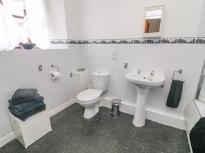 Casa de banho com sanita, lavatório e um pequeno contentor de lixo.