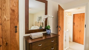 Une commode en bois avec des tiroirs, un miroir et un vase contenant des fleurs blanches.
