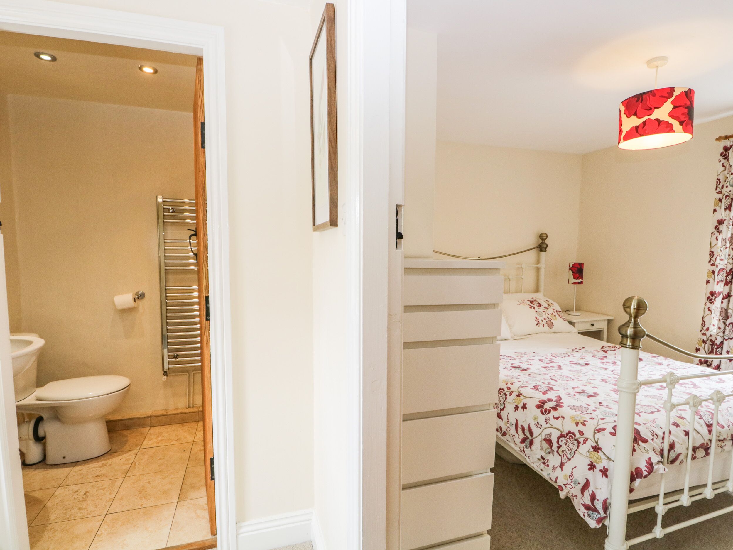 A bedroom with a bed, a bedside table, a lamp, and a window with curtains.