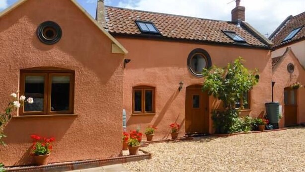 A traditional building with a sloped roof, multiple windows, and a gravel courtyard. - The Old Stable (Weston-super-Mare)