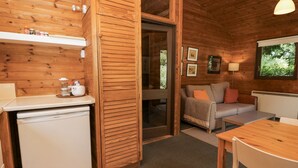Un intérieur de chalet chaleureux comprenant un coin cuisine, un espace repas et un coin salon avec un canapé et une table.