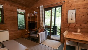 L’intérieur chaleureux d’un chalet, avec un revêtement mural en bois, un canapé, une table et une bibliothèque.
