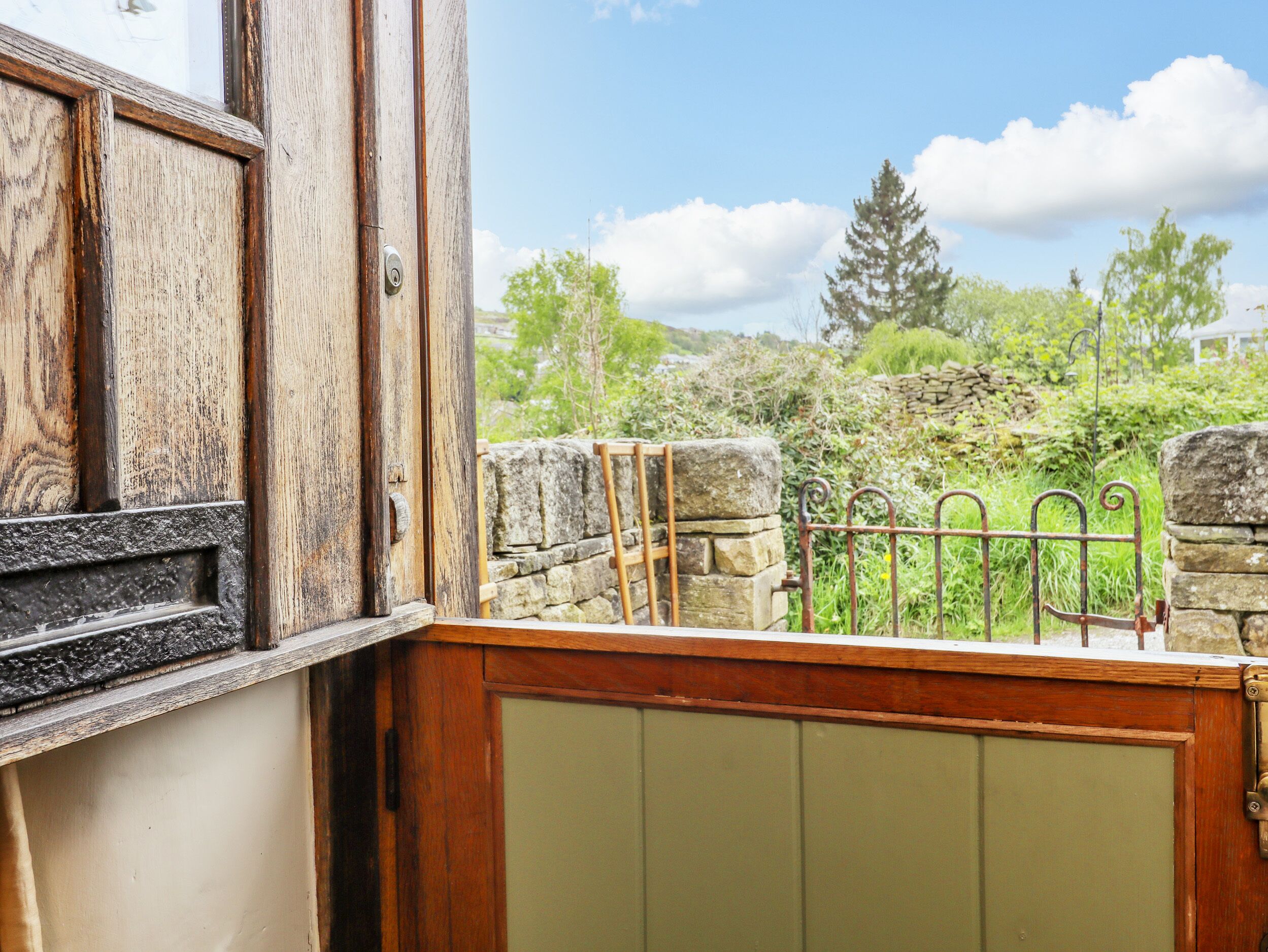 A rustic wooden door with a metal gate leading to a stone wall.