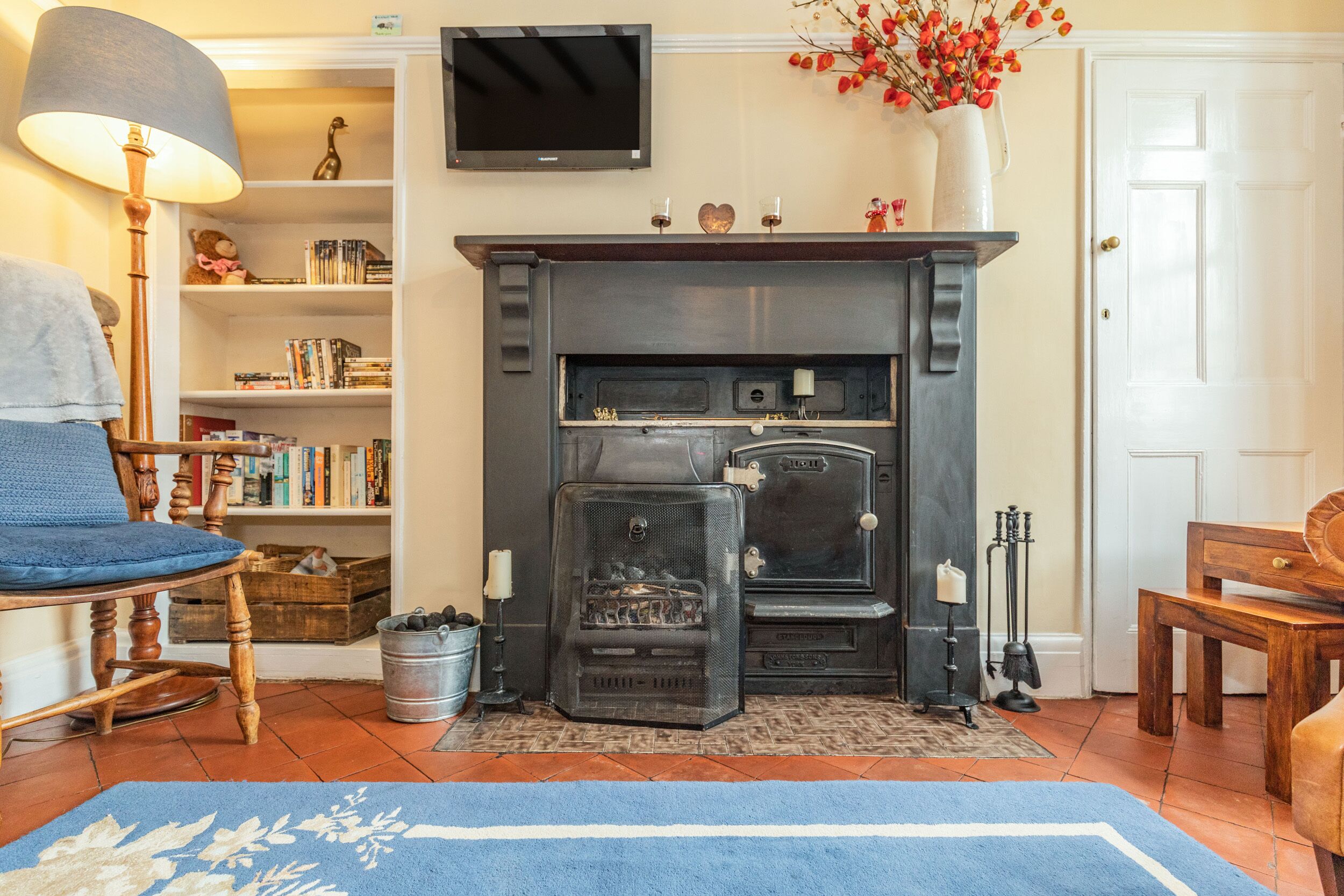 A cozy living room with a fireplace, bookshelves, a television, and a blue rug.