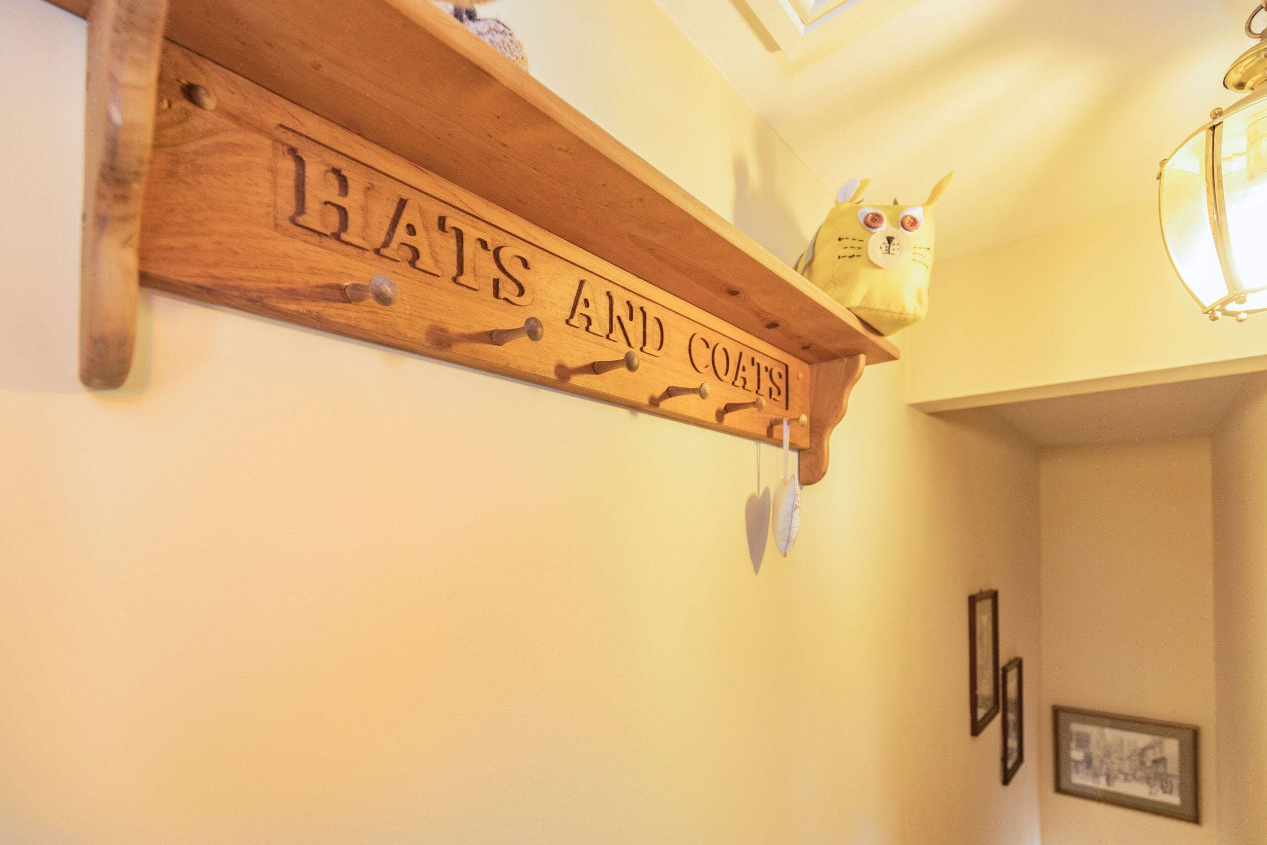 Een houten bord met de tekst 'HATS AND COATS' aan een muur.