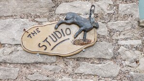 Un muro de piedra con un letrero que dice "THE STUDIO" y una escultura de un caballo.