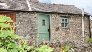 Un edificio de piedra con una puerta verde y una ventana pequeña.