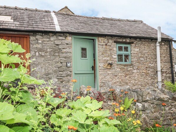 A stone building with a green door and a small window.