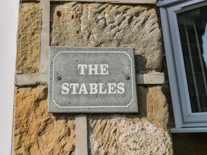 Un letrero que dice THE STABLES sujeto a una pared de piedra.