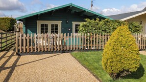 A green building with a gravel driveway and a wooden fence.