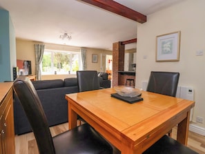 A dining area with a wooden table, black chairs, and a clear glass bowl on the table.