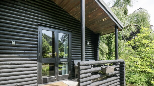A log cabin with a wooden porch and a glass door. - Grasmere (Ulverston)