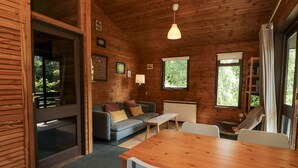 A cozy cabin interior with a wooden ceiling, a sofa, a dining table, and a bookshelf. - Grasmere (Ulverston)