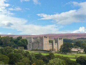A castle with multiple towers, surrounded by lush greenery and a clear sky. - The Round House (Leyburn)
